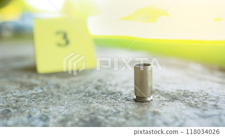Spent bullet casing lying on dark ground with blur number 3 sign. Concepts of criminal investigations Spent bullet casing lying on dark ground with blur number 3 sign. Concepts of criminal investigations 118034026