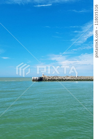 Serene Seaside with Lighthouse Under Clear Blue Sky - Coastal Recreation, Travel Concept Serene Seaside with Lighthouse Under Clear Blue Sky - Coastal Recreation, Travel Concept 118035316