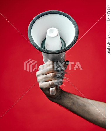 Werewolf's hand with long fingers and nails, paw holding modern smartphone with blank screen against red studio background. 118035935