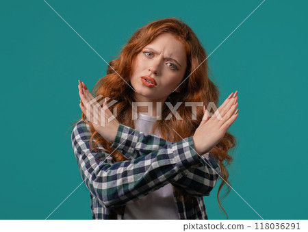 No, never, pretty red haired woman disliking and rejecting gesture by stop crossing hands sign. Cute girl disapproving sign make negation sign on blue studio background. Ban, timeout. 118036291