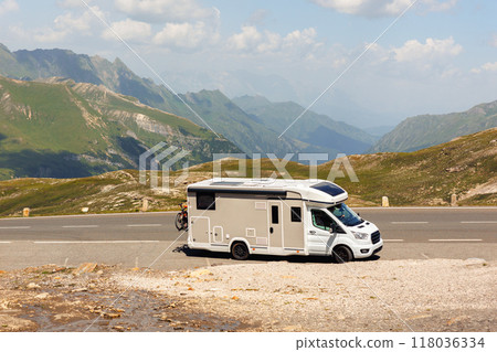 Scenic view big modern white family rv camper van vehicle drive Europe highway road alpine pass mountain sunny summer day. Rving motorhome lifestyle travel adventure tourism trip Alps journey concept 118036334