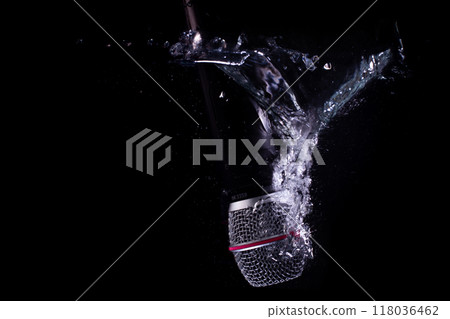 Dynamic capture of a microphone hitting water and creating splashes against a black background. 118036462