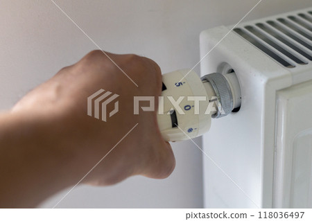 Hand turning the thermostat on a radiator to control temperature. Hand turning the thermostat on a radiator to control temperature. 118036497