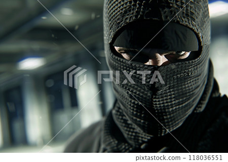 Close-up of a masked man in a dimly lit interior, creating an intense and mysterious atmosphere. Close-up of a masked man in a dimly lit interior, creating an intense and mysterious atmosphere. 118036551