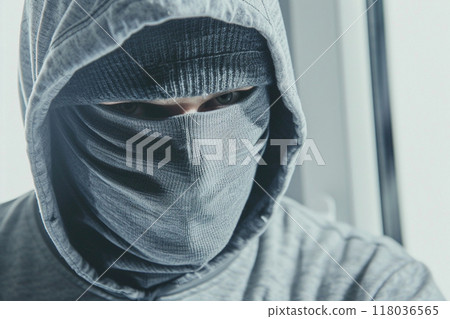 A person wearing a hooded jacket and a face mask, with a serious and secretive expression. 118036565