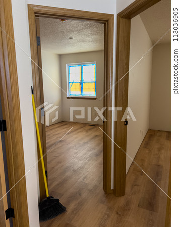 A view of a partially renovated home interior showcasing newly installed wood-look vinyl plank flooring. The scene includes wooden door frames, a room with a window taped for painting, and a hallway 118036905