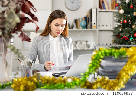Sad woman bookkeeper working during Christmastime Sad woman bookkeeper working during Christmastime 118036958