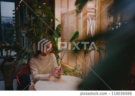 Woman typing write message on smart phone in a modern cafe.  118036986