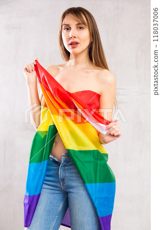 Scantily clad woman posing in studio wrapped in rainbow flag 118037006