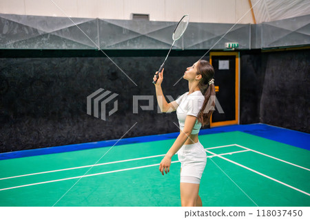 Sports young woman with racket and shuttlecock is exercising, playing in badminton on inside court Sports young woman with racket and shuttlecock is exercising, playing in badminton on inside court 118037450