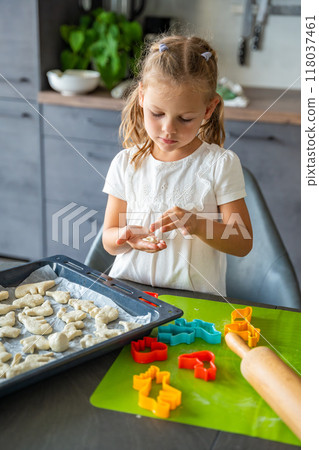 Little girl making cookie with dough using animal shape cutters in the home kitchen, Family concept Little girl making cookie with dough using animal shape cutters in the home kitchen, Family concept 118037461