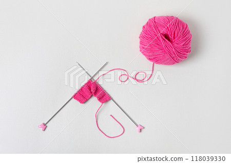 Pink knitted wool on gray background with knitting needles for knitting warm clothes and hobbies needlework Pink knitted wool on gray background with knitting needles for knitting warm clothes and hobbies needlework 118039330