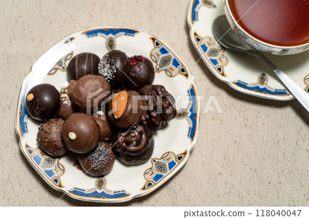 Assortment of fine filled chocolate bonbons on a plate with a cup of red tea. Assortment of fine filled chocolate bonbons on a plate with a cup of red tea. 118040047