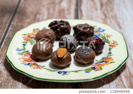 Assortment of fine chocolate bonbons on a plate on a wooden table. 118040048