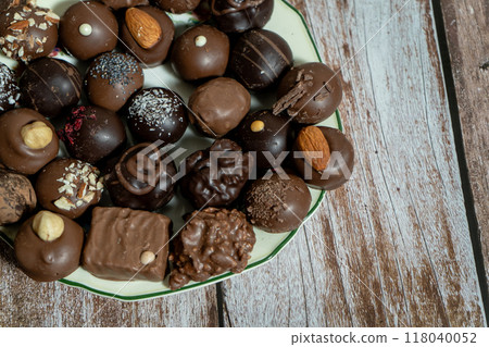 Assortment of fine chocolate bonbons on a plate on a wooden table. Assortment of fine chocolate bonbons on a plate on a wooden table. 118040052
