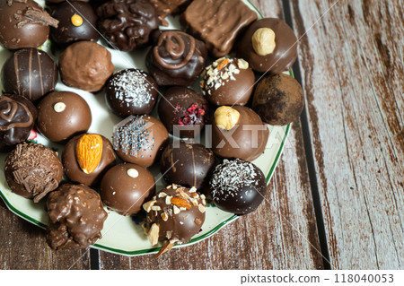 Assortment of fine chocolate bonbons on a plate on a wooden table. Assortment of fine chocolate bonbons on a plate on a wooden table. 118040053