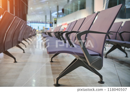 Empty chairs in airport departure hall, blurred airplane in the background. Empty chairs in airport departure hall, blurred airplane in the background. 118040507