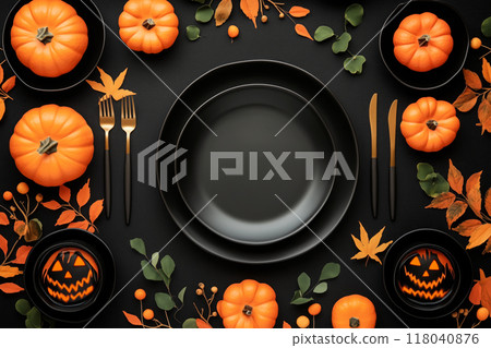 Halloween themed table setup with orange pumpkins, black skulls, red leaves, and black cutlery on a dark background 118040876