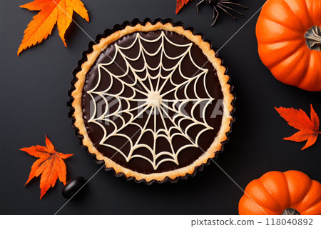 Chocolate tart with spider web design and spider decoration on black background. Concept of Halloween dessert Chocolate tart with spider web design and spider decoration on black background. Concept of Halloween dessert 118040892