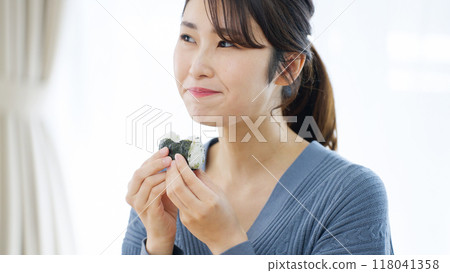 A woman eating rice ball with a smile 118041358