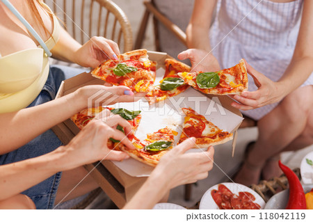 girls take a slice of pizza from a box in the park, fresh tasty pizza 118042119