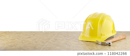 Yellow Construction Hard Hat and Hammer Resting on Particleboard Banner Isolated on a White Background. Yellow Construction Hard Hat and Hammer Resting on Particleboard Banner Isolated on a White Background. 118042266