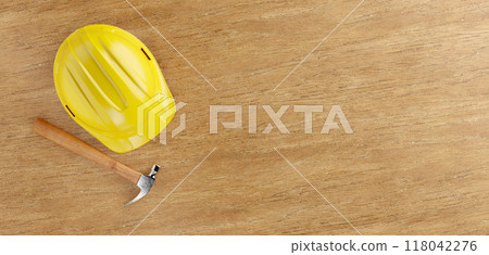 Overhead of Yellow Hard Hat and Hammer on a Wood Surface with Room For Text. Overhead of Yellow Hard Hat and Hammer on a Wood Surface with Room For Text. 118042276