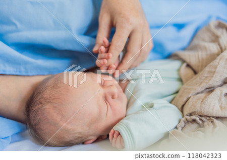 A baby lies with the mother after childbirth, resting peacefully. The serene moment captures the bond between mother and child as they begin their journey together. The hospital environment ensures a 118042323