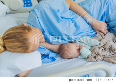 A baby lies with the mother after childbirth, resting peacefully. The serene moment captures the bond between mother and child as they begin their journey together. The hospital environment ensures a A baby lies with the mother after childbirth, resting peacefully. The serene moment captures the bond between mother and child as they begin their journey together. The hospital environment ensures a 118042327