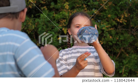 Girl, boy children kids drink water after active games in nature outside. Children replenish thirst, water balance in body, get rid of dehydration. Children kids greedily drink water from bottle. Girl, boy children kids drink water after active games in nature outside. Children replenish thirst, water balance in body, get rid of dehydration. Children kids greedily drink water from bottle. 118042644