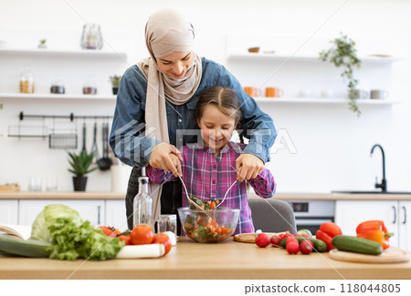 Muslim mother and daughter making salad together in kitchen 118044805