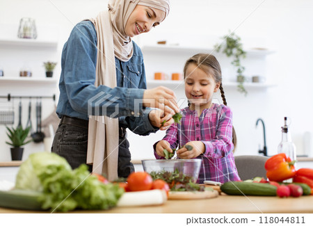 Muslim mother and daughter preparing salad in kitchen Muslim mother and daughter preparing salad in kitchen 118044811