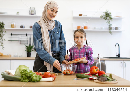 Muslim mother and daughter cooking fresh salad in modern kitchen Muslim mother and daughter cooking fresh salad in modern kitchen 118044814