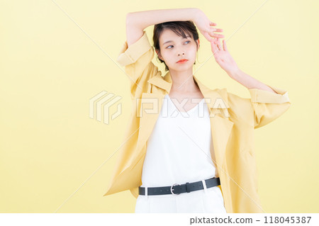 穿著黃色背景夾克擺姿勢的年輕女子 118045387