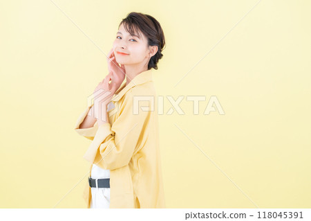 穿著黃色背景夾克擺姿勢的年輕女子 118045391