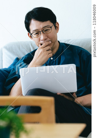 一個操作帶沙發的電腦的男人 118046009