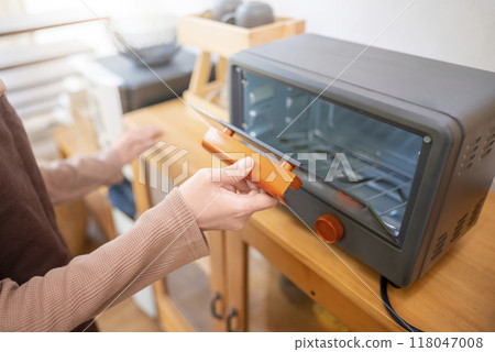 A woman is holding a toaster oven handle 118047008