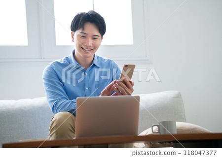 A man operating a smartphone while looking at a computer 118047377