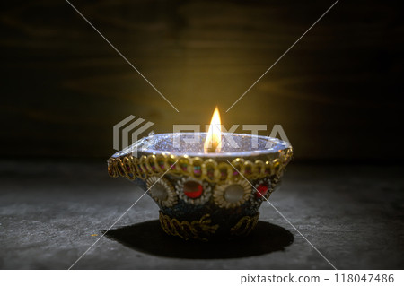 A blue and gold decorated pot with a blue and white design sits on a dark surface 118047486