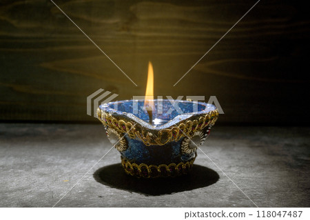 A blue and gold decorated pot with a blue and white design sits on a dark surface 118047487