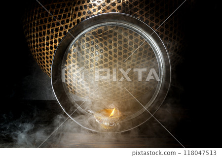 Diya oil lamp on the sieve. The candle is lit and the light is shining through the mesh Diya oil lamp on the sieve. The candle is lit and the light is shining through the mesh 118047513