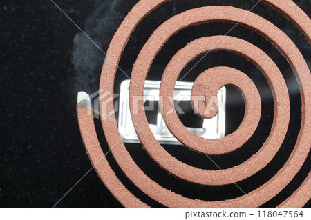 A mosquito coil with smoke coming out of it A mosquito coil with smoke coming out of it 118047564
