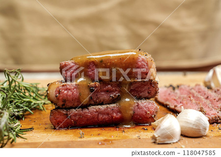 Three pieces of picanha meat are stacked on top of each other on a wooden cutting board 118047585