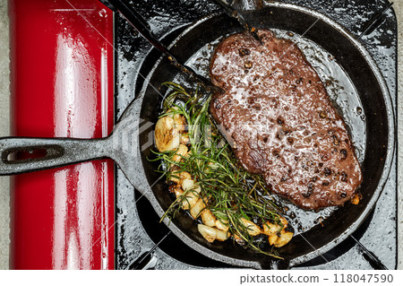 A person is cooking a picanha steak in a pan on a stove A person is cooking a picanha steak in a pan on a stove 118047590