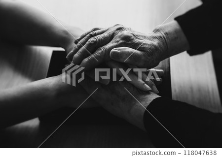 A Christian grandmother's hand resting on a Bible in a church, comforting, blessing and praying A Christian grandmother's hand resting on a Bible in a church, comforting, blessing and praying 118047638