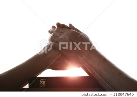 Hands of an elderly Christian holding hands, comforting each other, praying and worshiping, and a Bible in a church Hands of an elderly Christian holding hands, comforting each other, praying and worshiping, and a Bible in a church 118047640