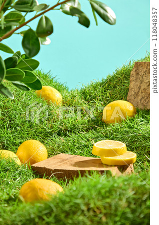 On blue background and green grass, fresh lemons and lemons slices decorated with wooden podium and branches leaves. Creative advertising scene with natural concept 118048357