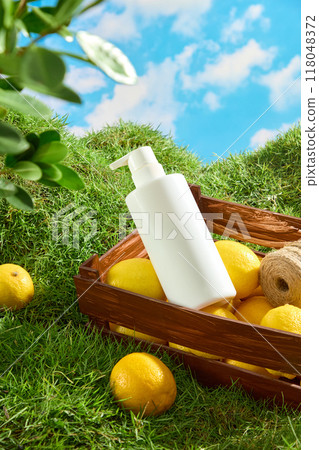 Mockup scene for cosmetic with natural vitamin C from lemon extract. A white pump bottle is displayed on a wooden basket filled with fresh lemons against a background of green grass and blue sky Mockup scene for cosmetic with natural vitamin C from lemon extract. A white pump bottle is displayed on a wooden basket filled with fresh lemons against a background of green grass and blue sky 118048372