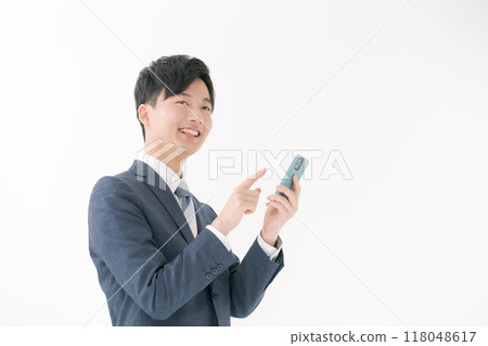 Smiling business person looking at smartphone 118048617