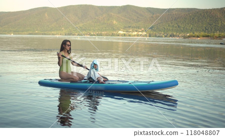 Experience the joy of a refreshing summer paddleboarding adventure on serene, calm waters Experience the joy of a refreshing summer paddleboarding adventure on serene, calm waters 118048807